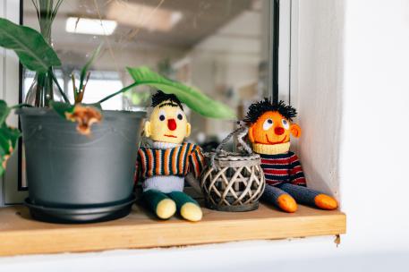 Pflegemutter sein eine Fensterbank mit einer Pflanze drauf und zwei gehäkelten Puppen von Ernie und Bert aus der Sesamstraße