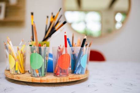 Pflegefamilie gründen  verschiedenen Bechr mit Buntstiften drinne, nach Farbe sortiert